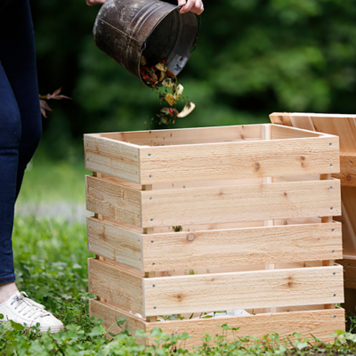 A wooden compost bin in a yard