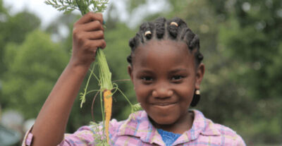 Young girl enjoys vaeggies at Schoolyard Roots